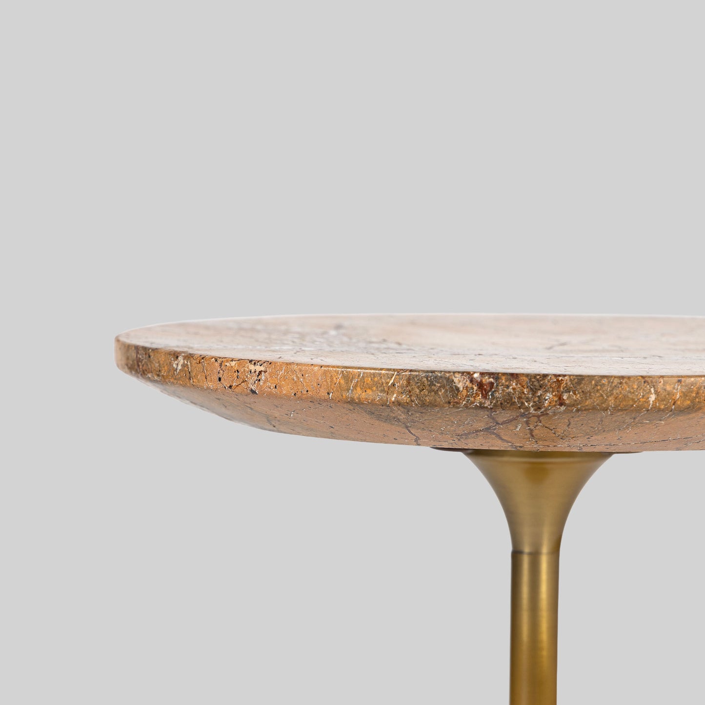 Small round cocktail table with marble top and brass base on a light gray background.