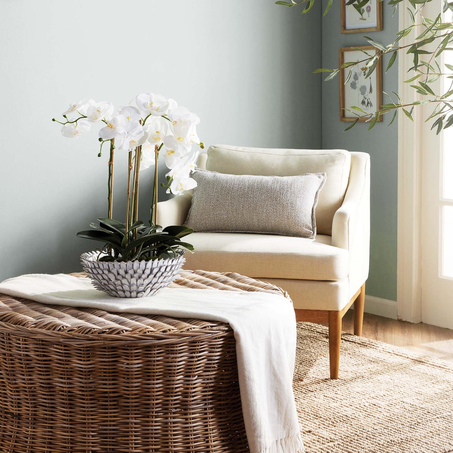Petal decorative terracotta bowl stylized with orchid on rattan ottoman in living room.