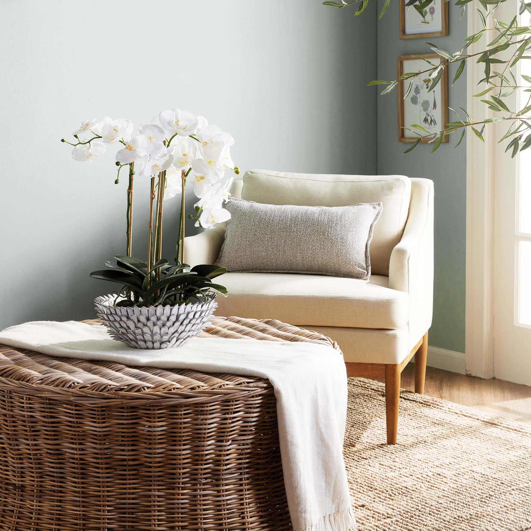 Petal decorative terracotta bowl stylized with orchid on rattan ottoman in living room.
