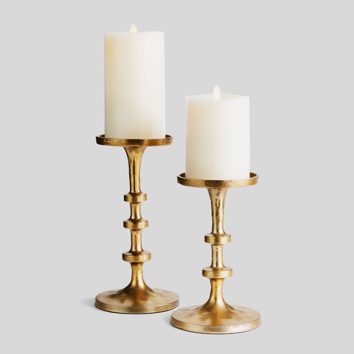 Petite minimalist pillar candleholders, set of 2, gold finish, with gray background.