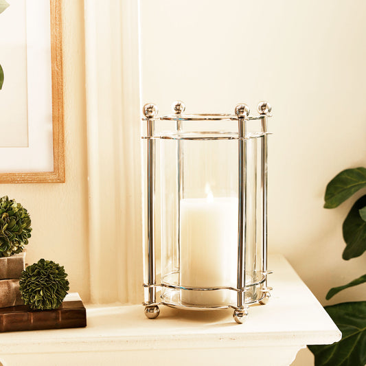 Small polished chrome finial hurricane candleholder on mantel.