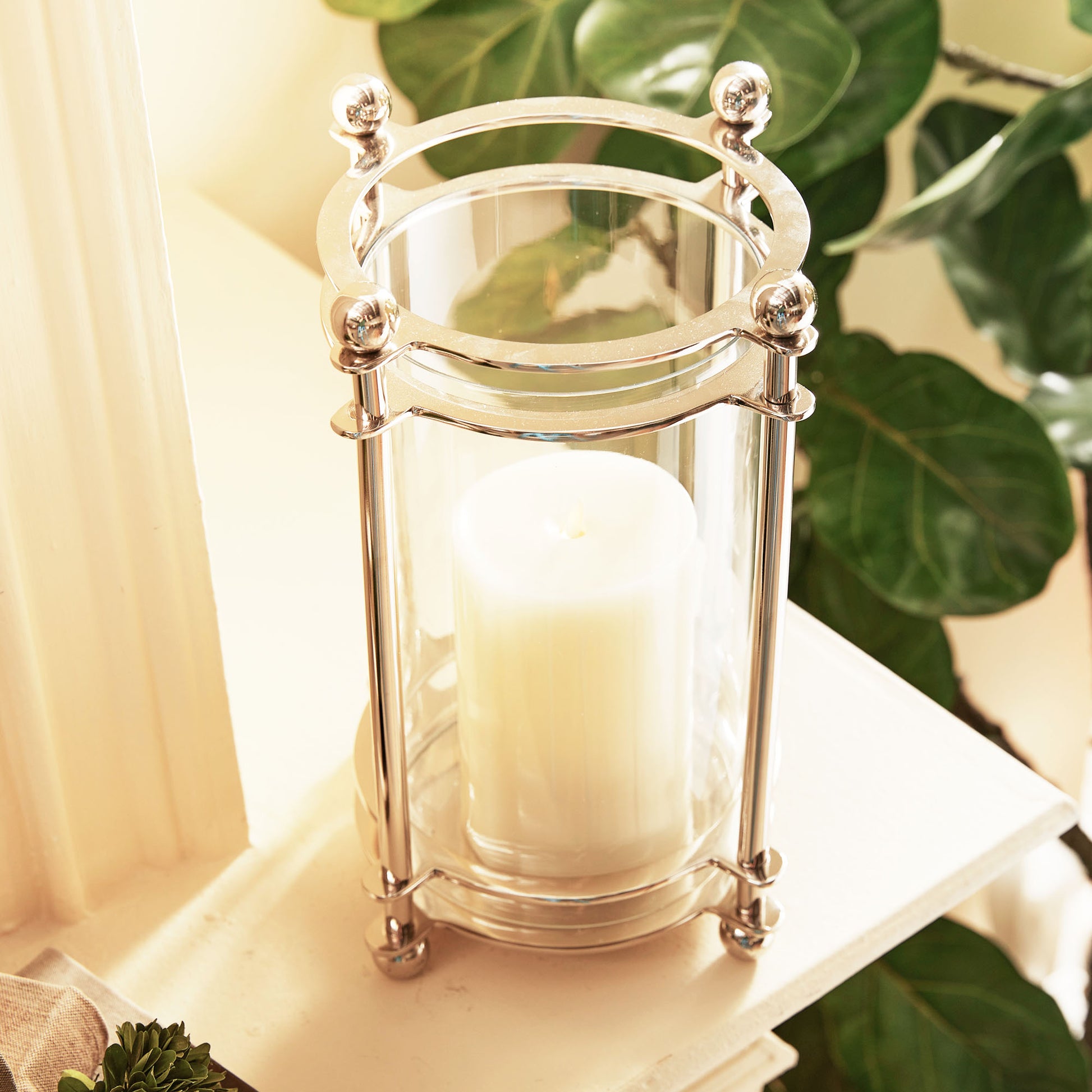 Top view of small polished chrome finial hurricane candleholder on mantel.