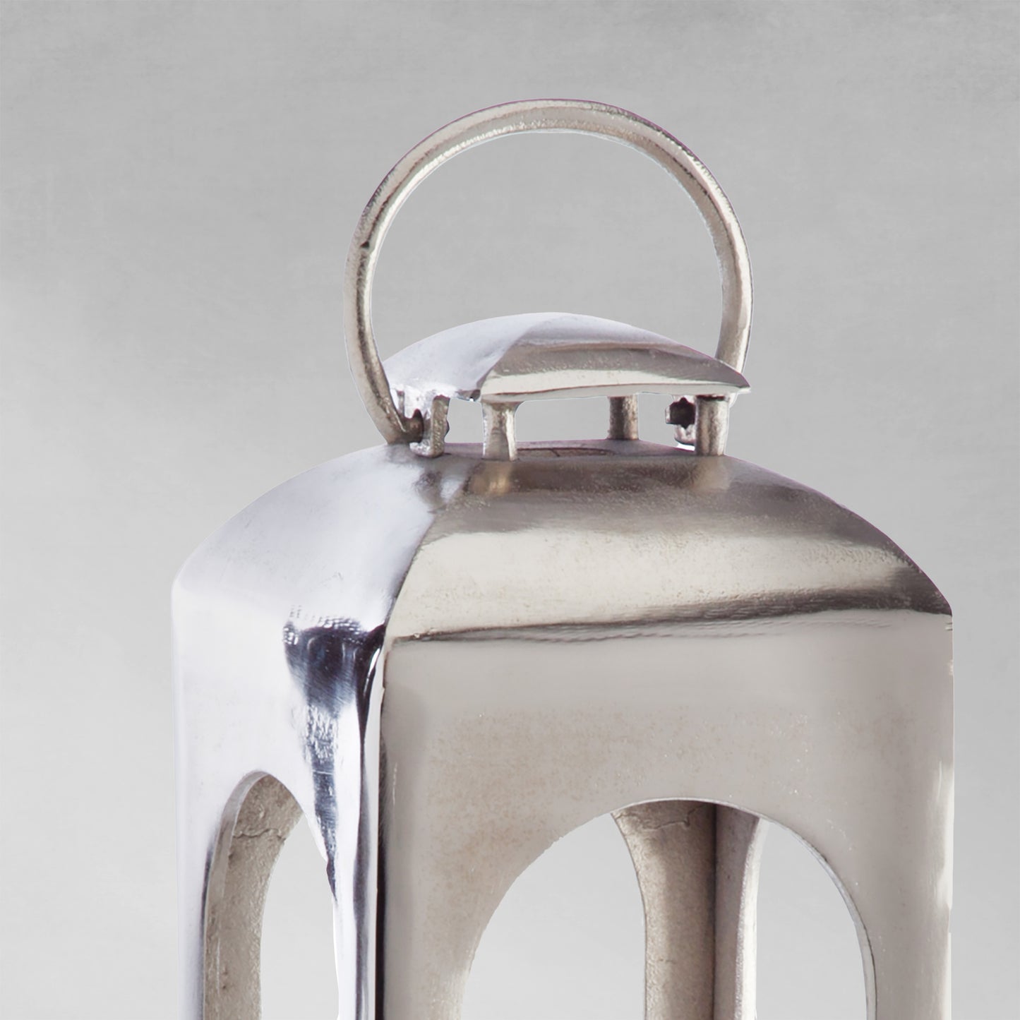 Polished metal lantern closeup view with gray background.