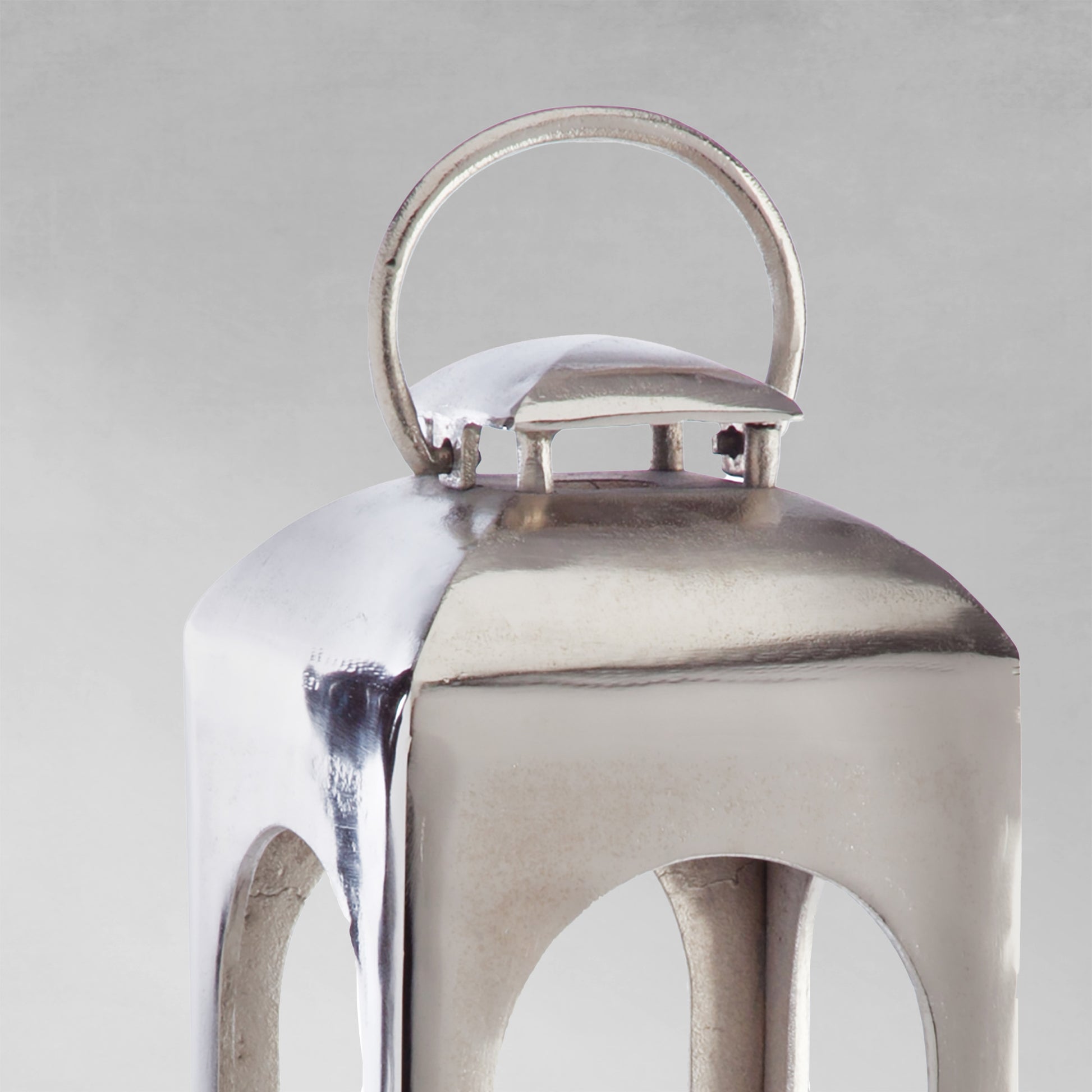 Polished metal lantern closeup view with gray background.