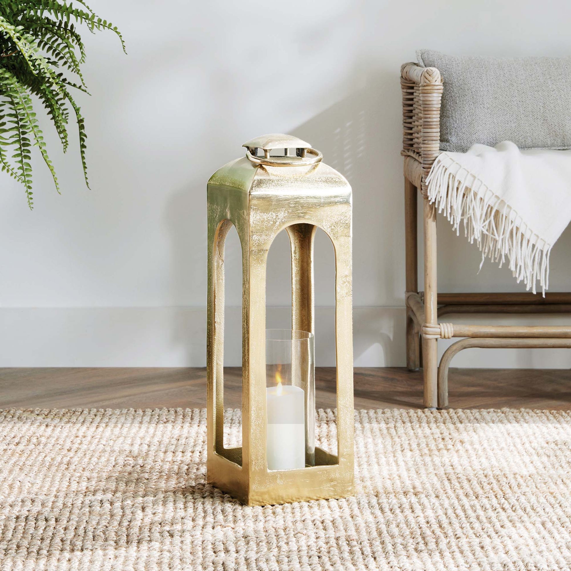 Polished metal lantern with champagne finish on rug.