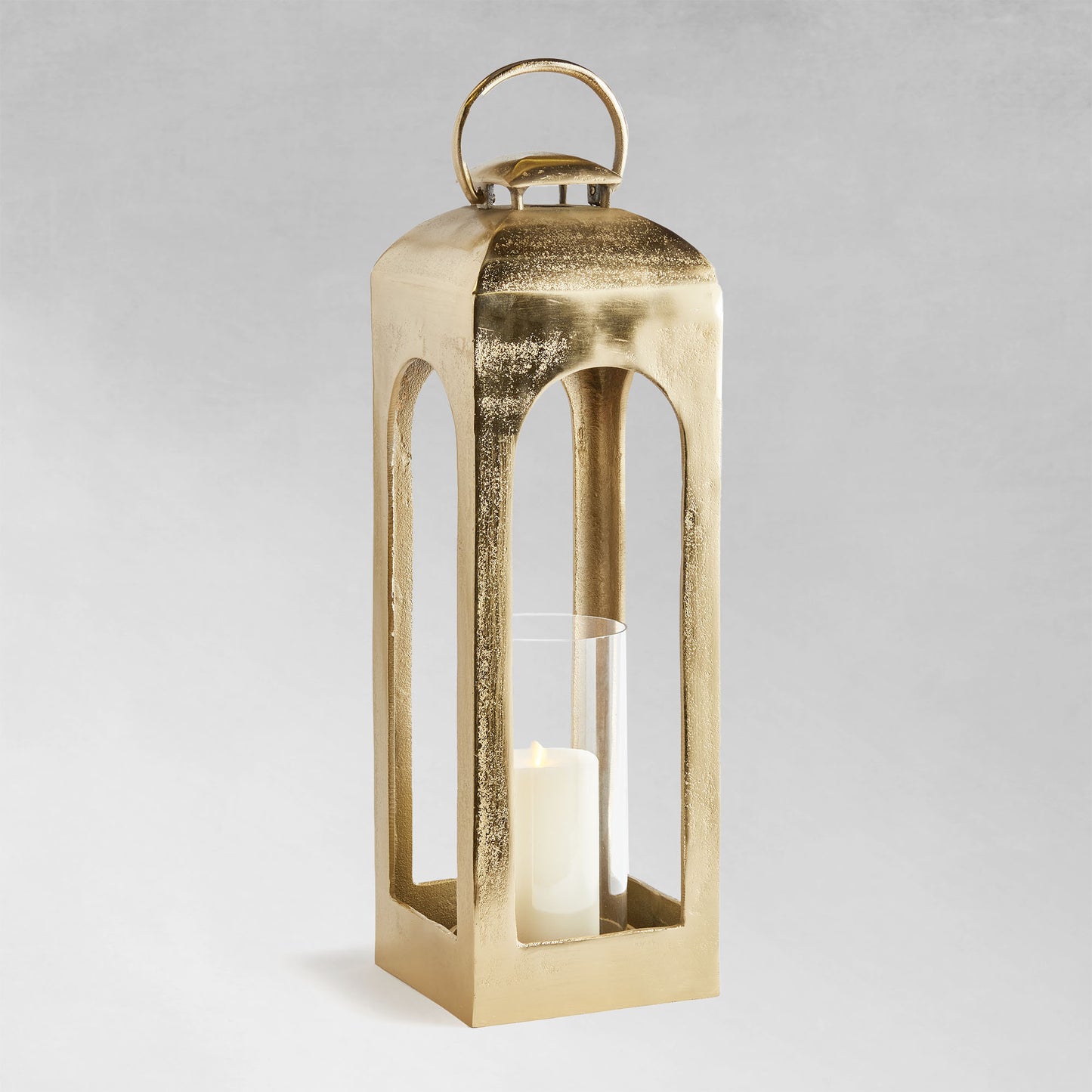 Large polished metal lantern with champagne finish with gray background.