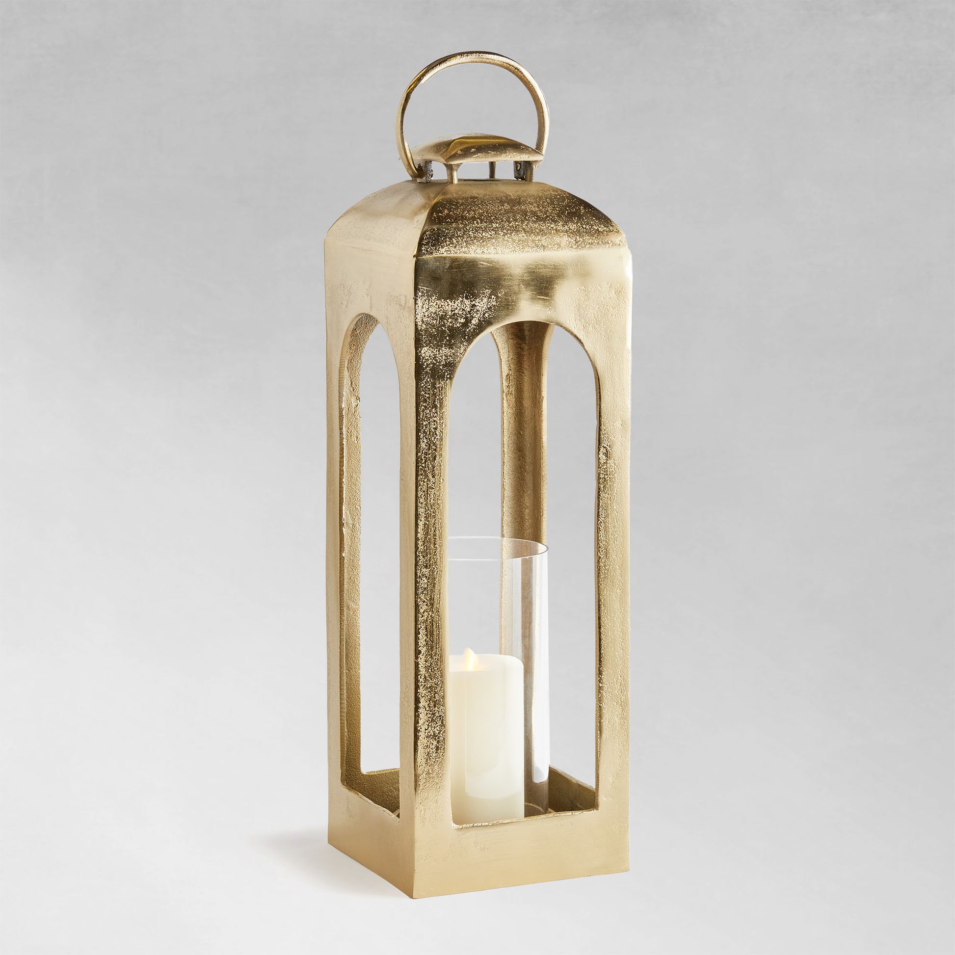Large polished metal lantern with champagne finish with gray background.