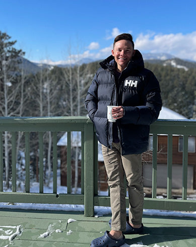 Adam on deck with snowcapped mountain in the background in Evergreen, Colorado.