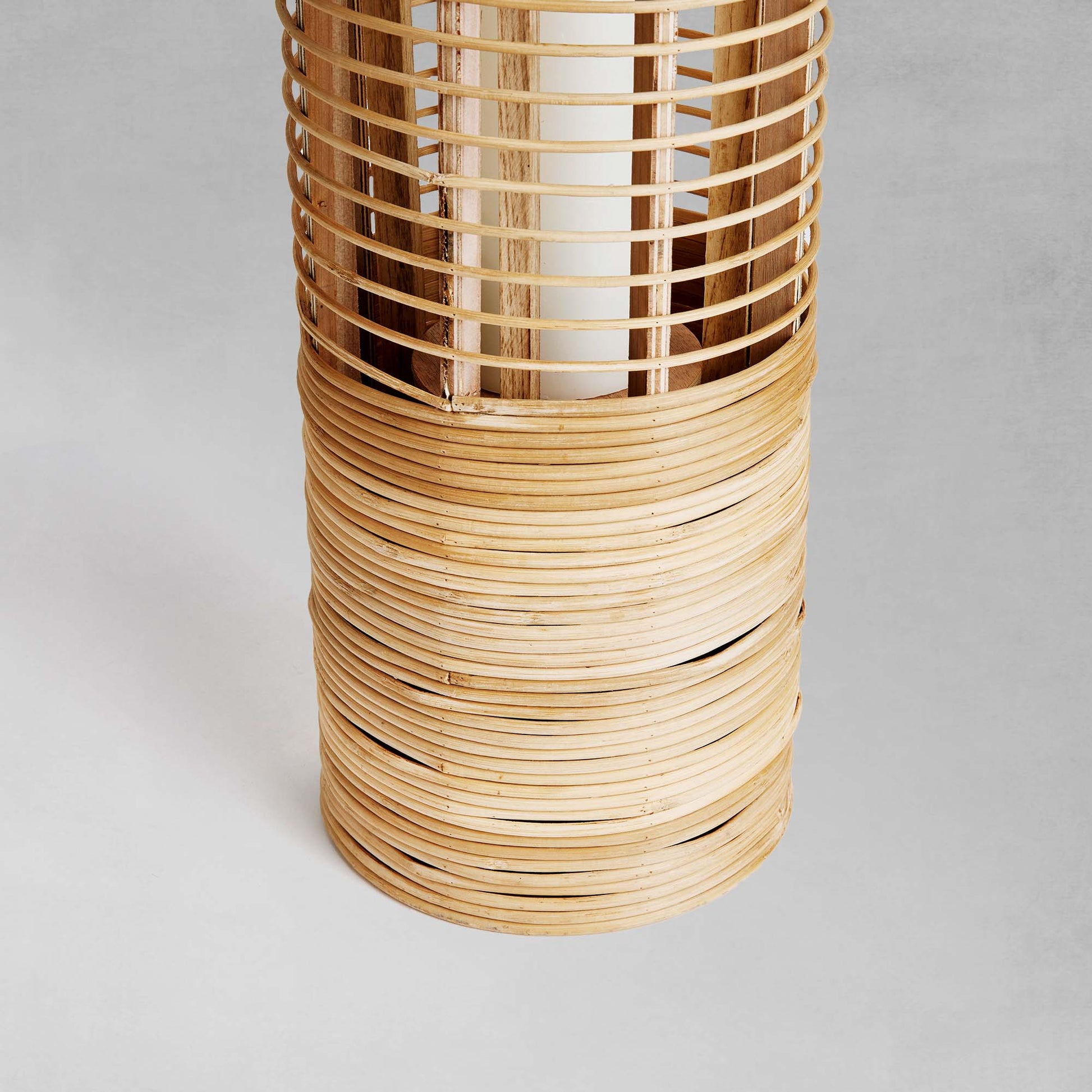 Rattan cylinder lantern, closeup view of lantern base,  with gray background.