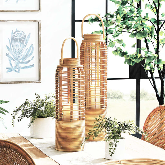 Small and large rattan cylinder lanterns stylized on table with plants.