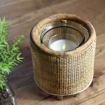 Rattan round hurricane candleholder on wooden table with rosemary.