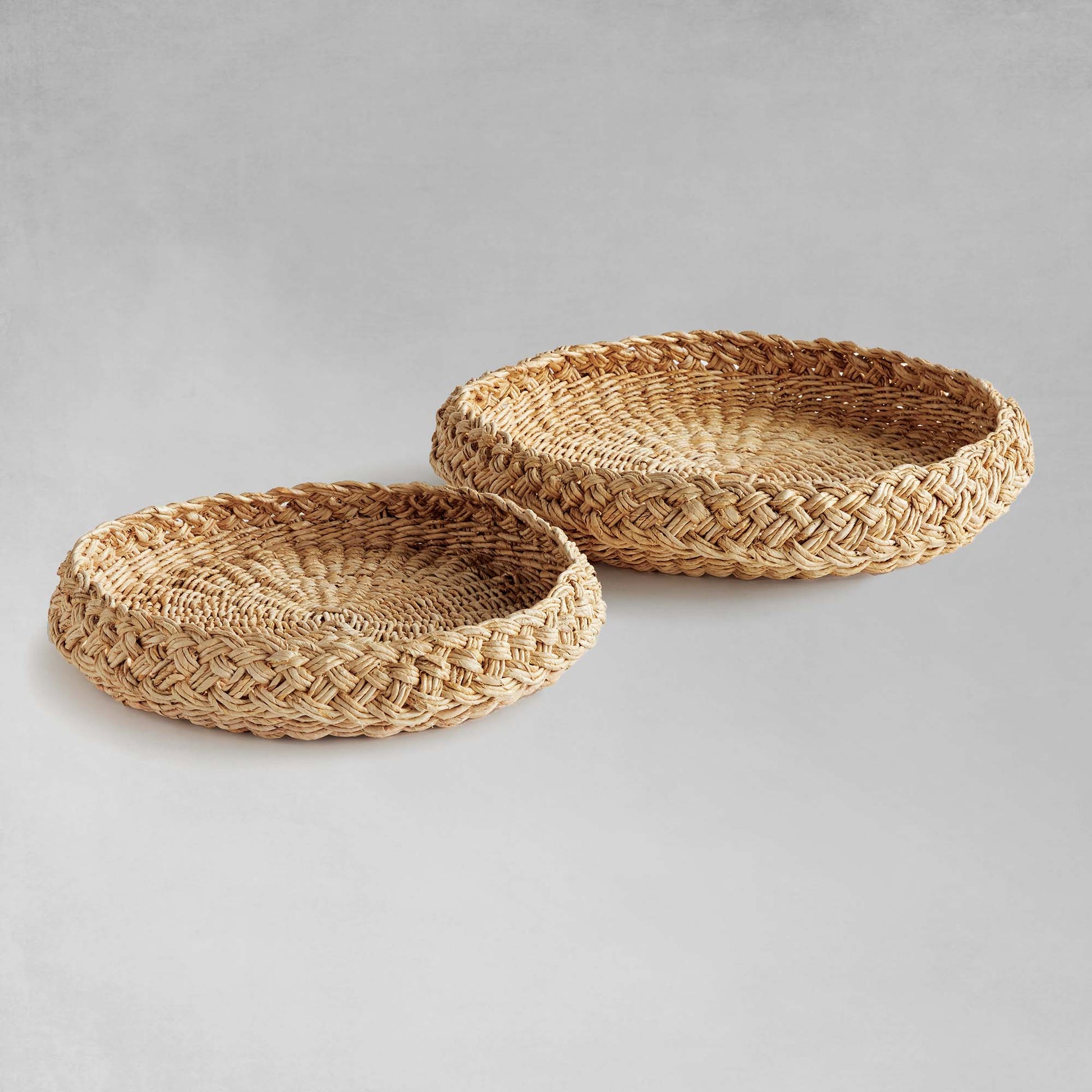 Round braided trays side by side with gray background.