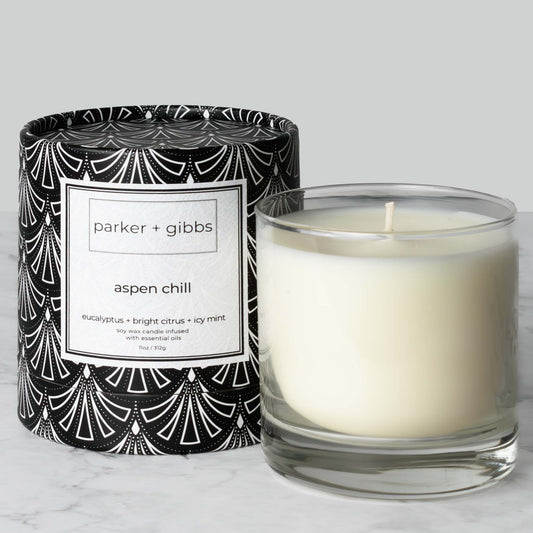Luxury scented soy wax blend candle with eucalyptus, citrus, and mint essential oils on marble table with gray background.