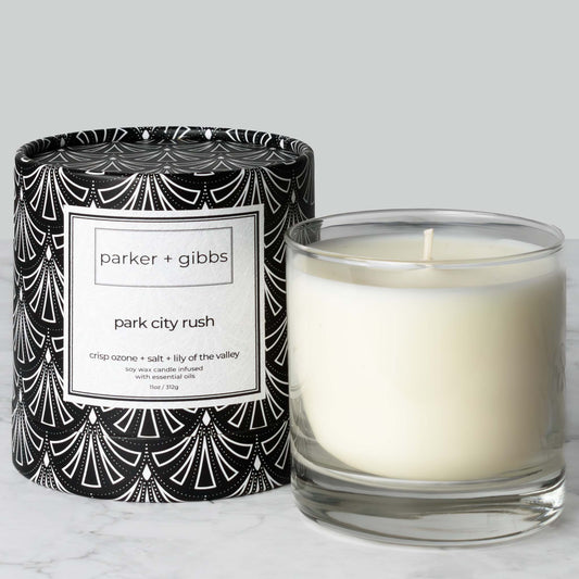 Luxury scented soy wax blend candle with ozone, salt, and lily of the valley essential oils on marble table with gray background.