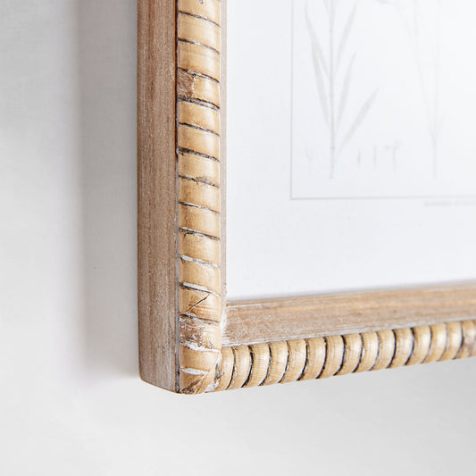 Sepia botanical gallery wall art set, closeup of rattan frame, on gray wall.