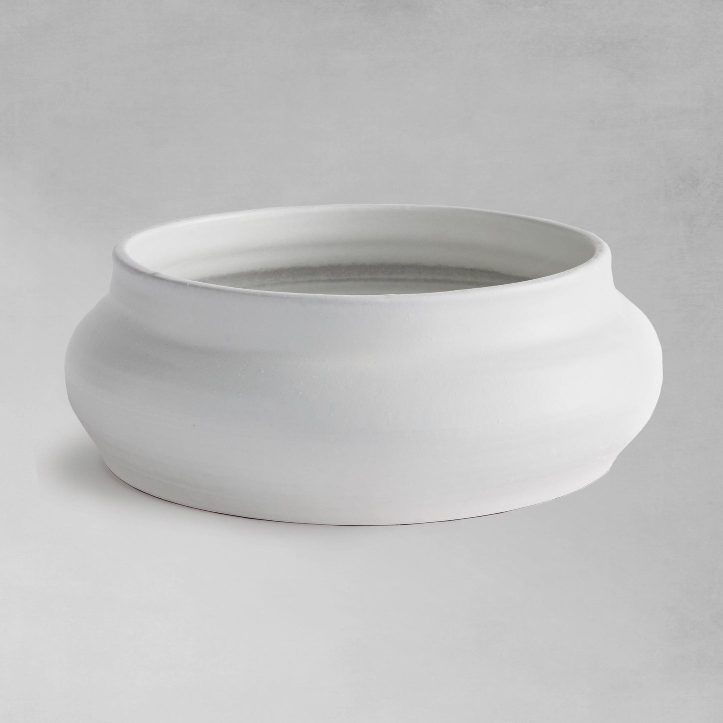 Smooth white decorative terracotta bowl with gray background.