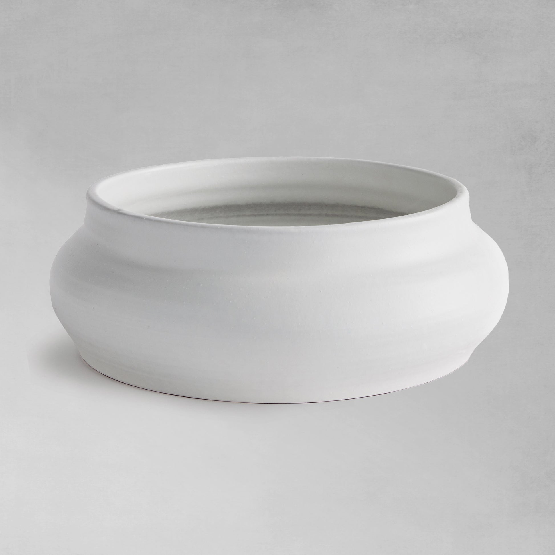 Smooth white decorative terracotta bowl with gray background.