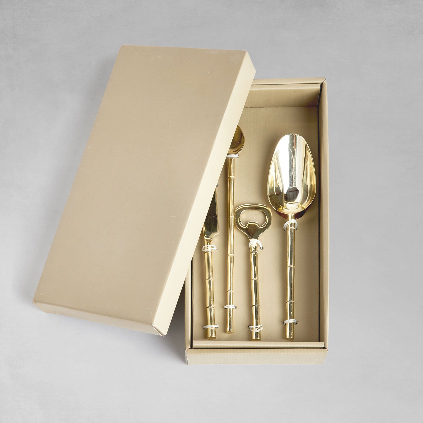 Stainless steel bamboo style barware tools set in gold and in box with gray background.