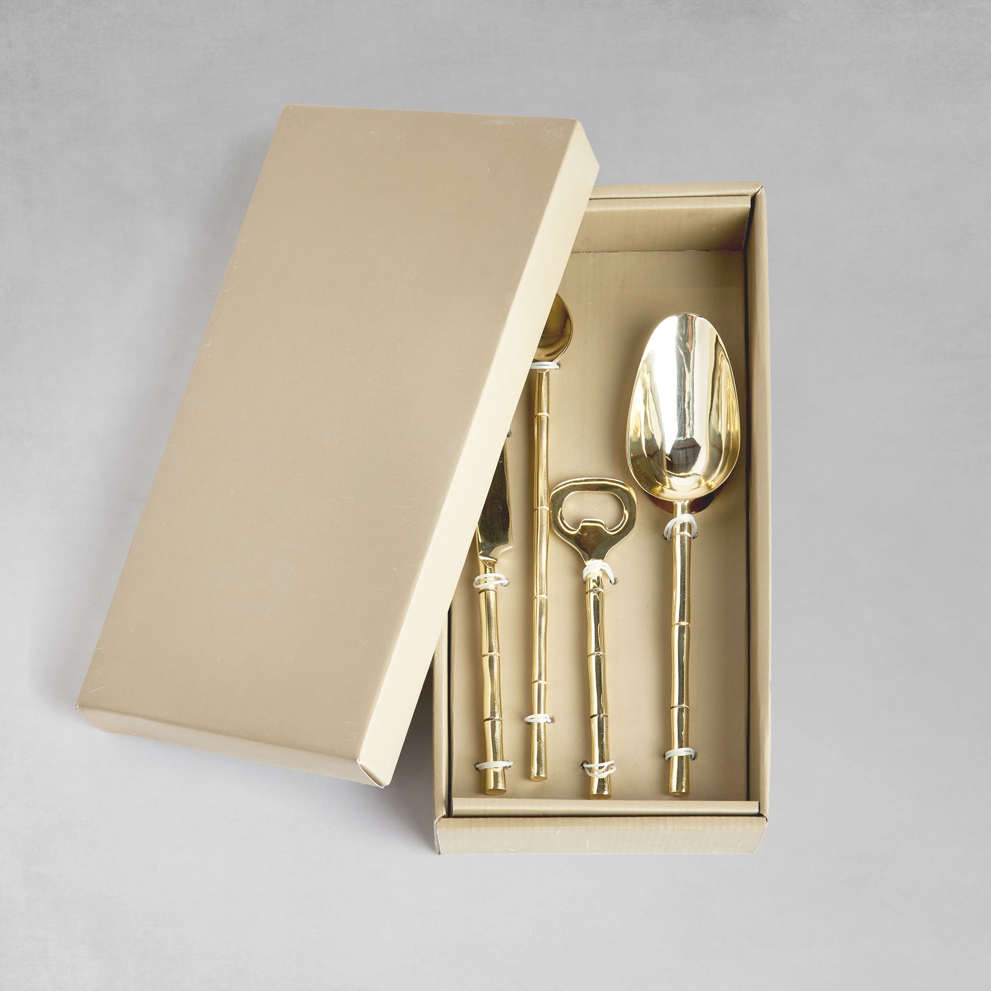 Stainless steel bamboo style barware tools set in gold and in box with gray background.
