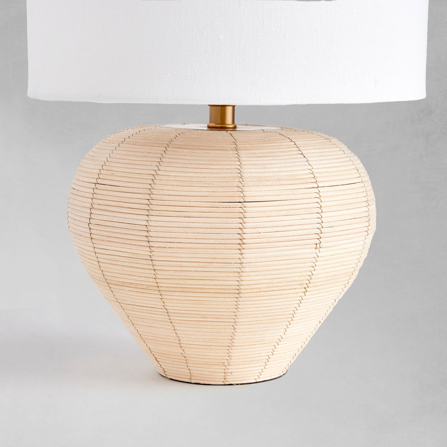 Tapered rattan mini lamp, closeup view of lamp base, with gray background.