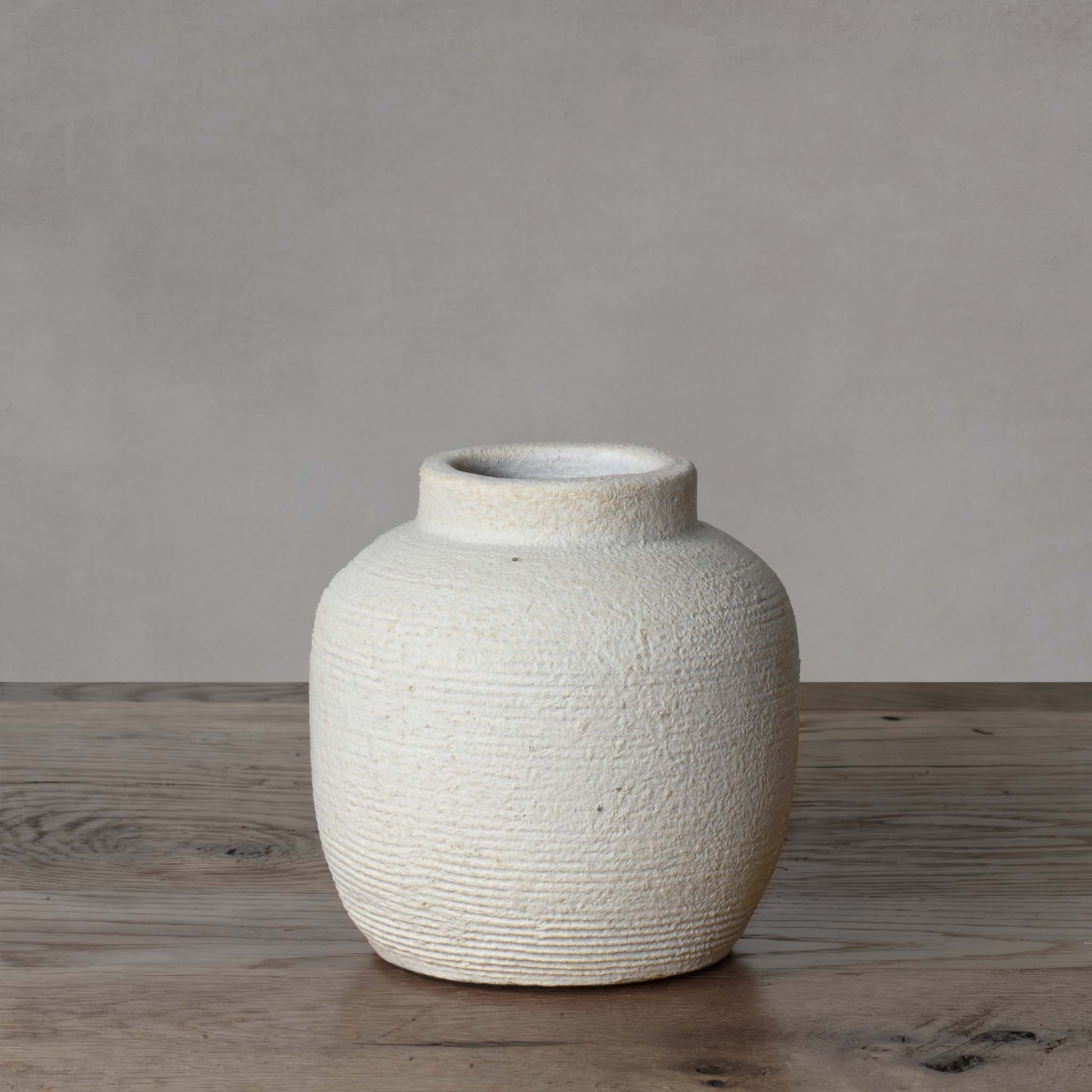 Small textured cement decorative vase with light gray background.