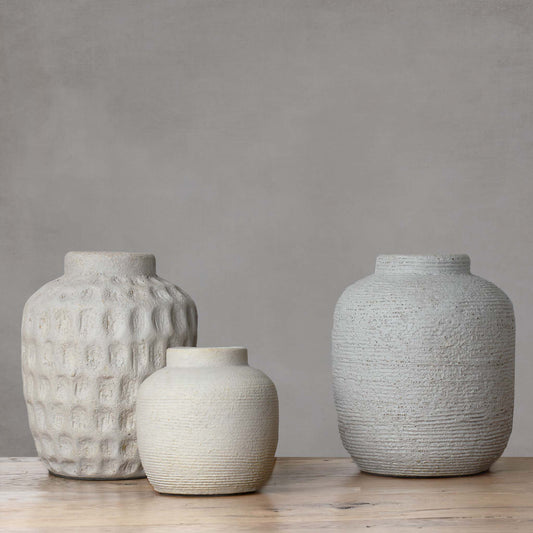 Set of three textured cement decorative vases with light gray background.