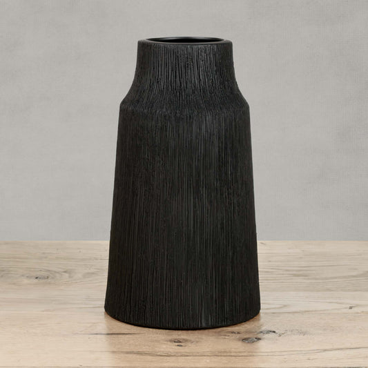 Textured ceramic large vase in matte black on wood table with gray background.