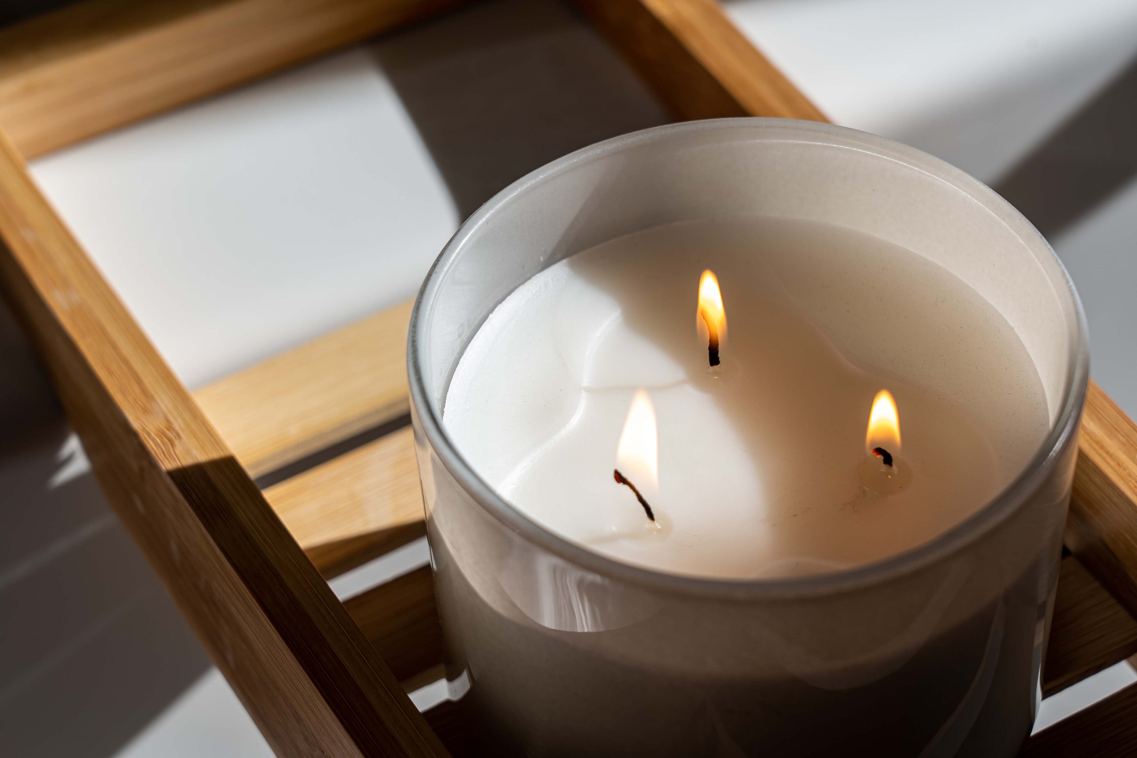 Three wick candle on teak tray.