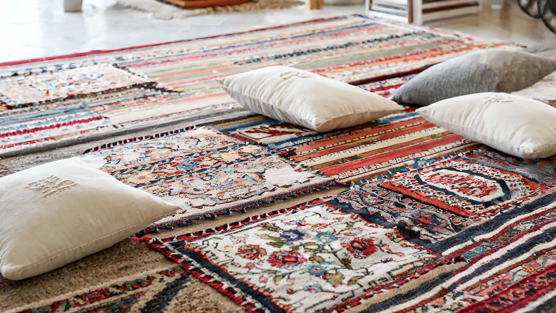 Turkish kilim rugs and pillows arranged on floor in Turkish textile factory.