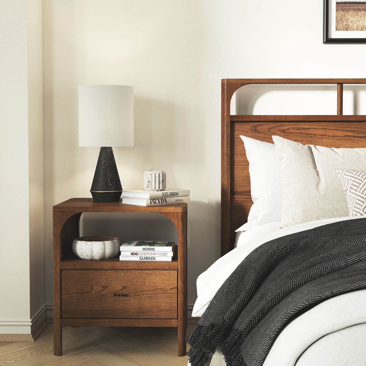 Wooden nightstand next to a bed with a lamp and books on top