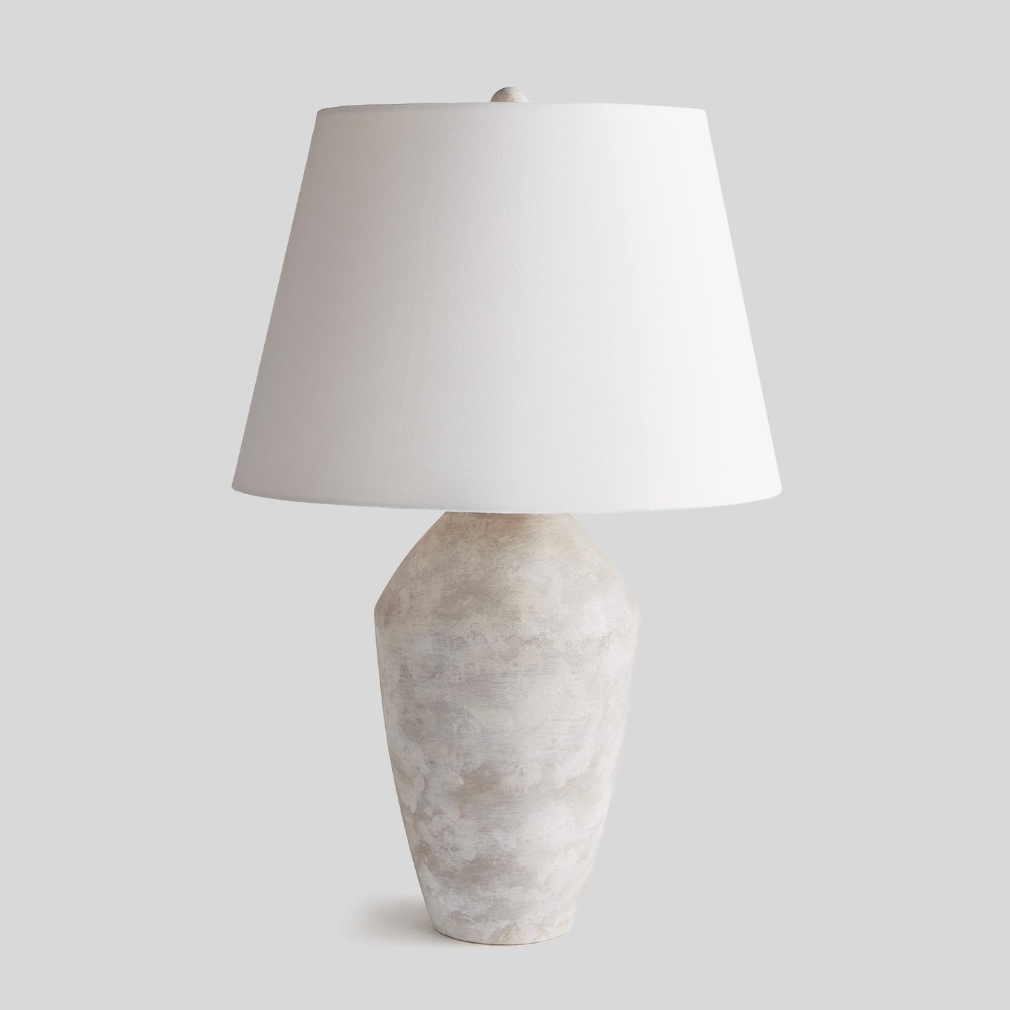 Weathered gray ceramic table lamp with light gray background.