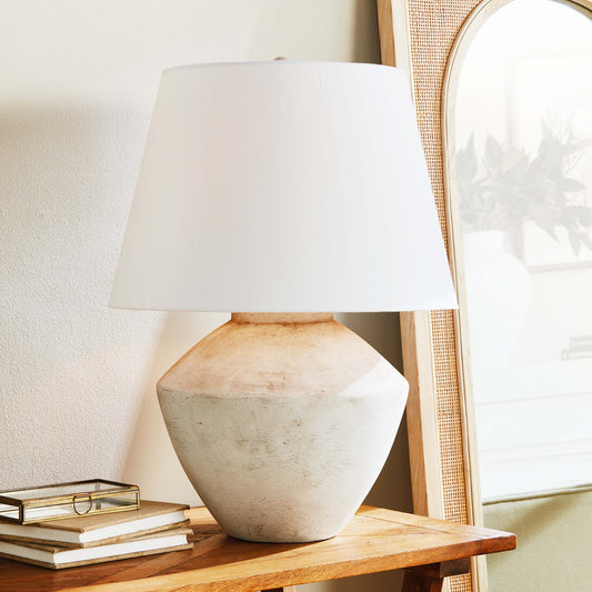 Weathered gray round ceramic table lamp stylized on console table.