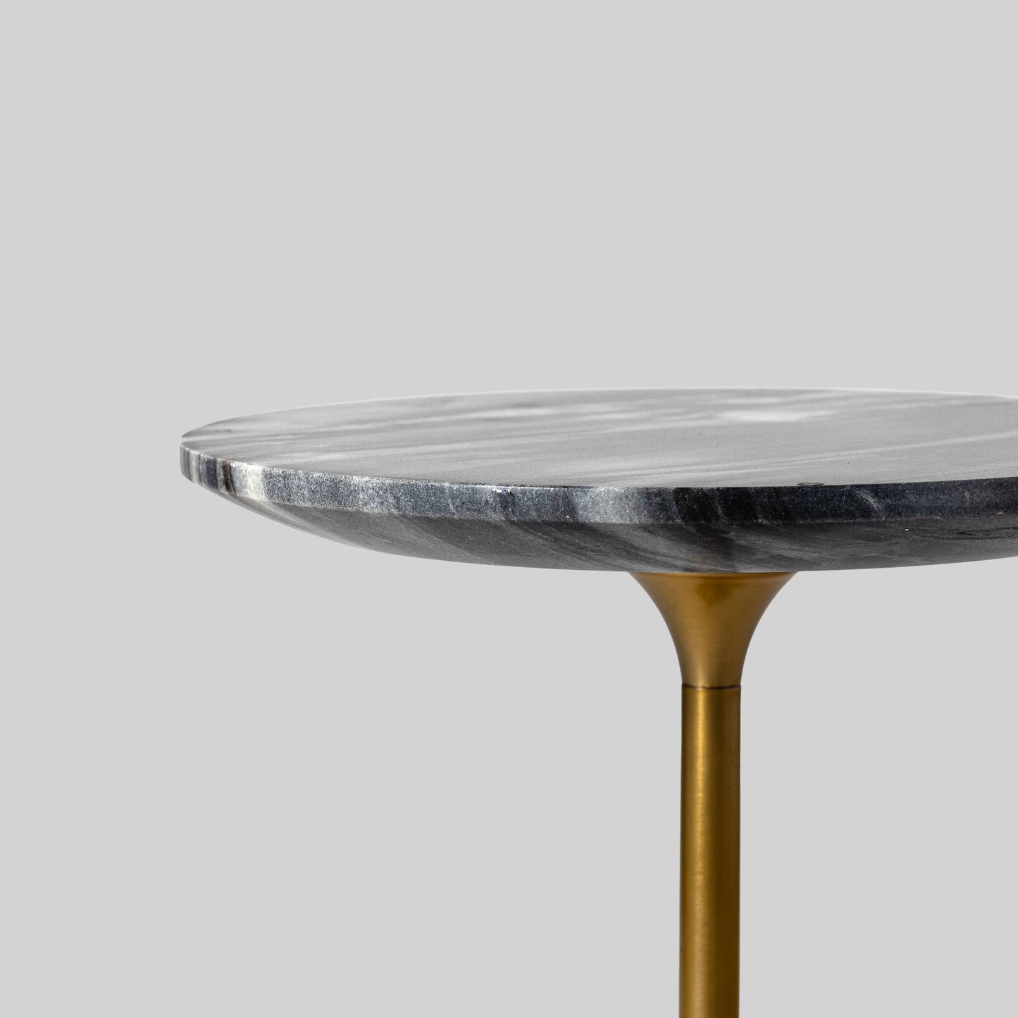 Small round cocktail table with marble top and brass base on a light gray background.