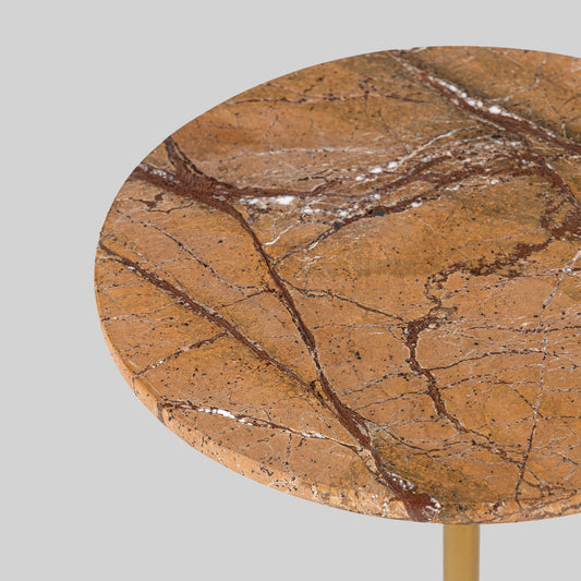 Small round cocktail table with marble top and brass base on a light gray background.