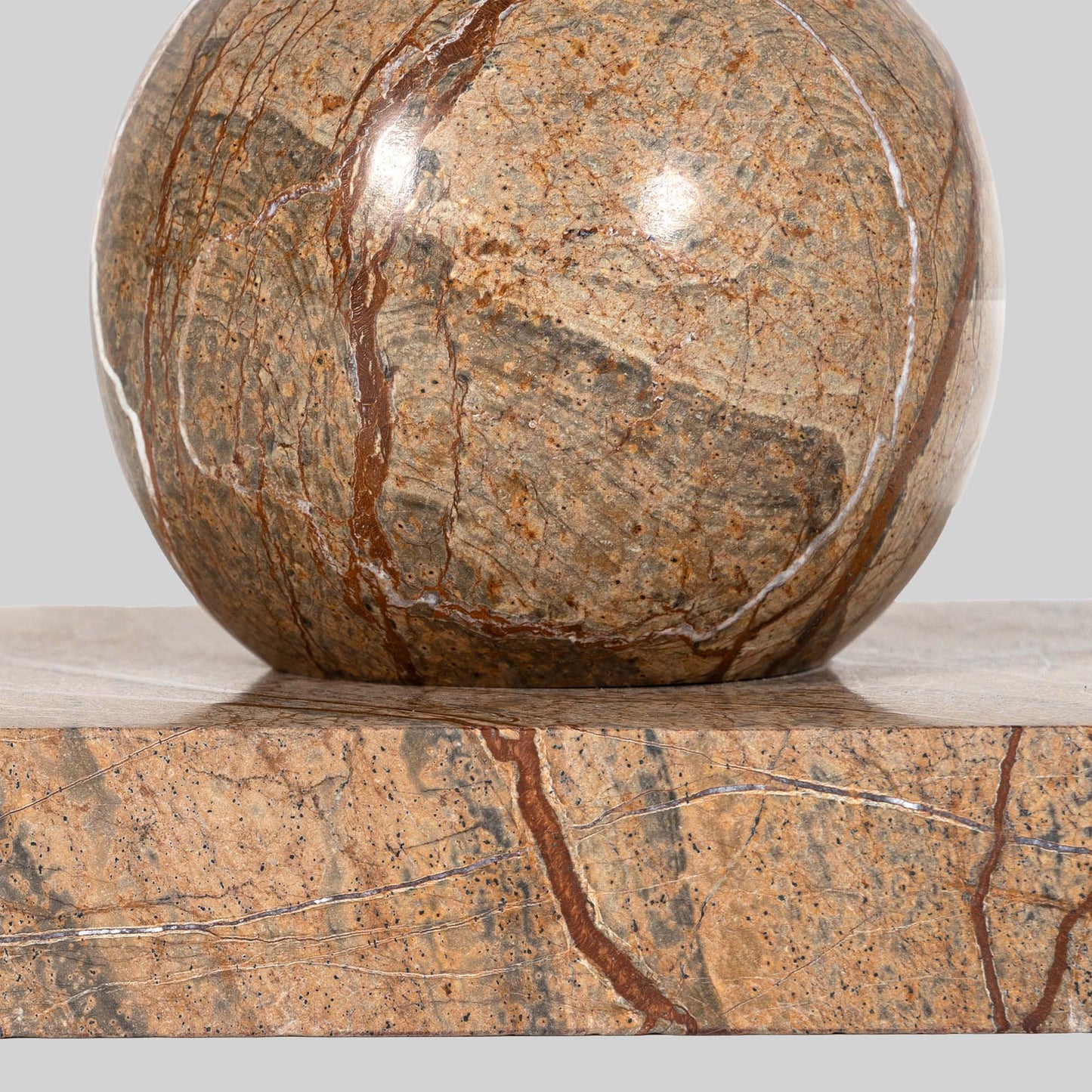 Small round cocktail table with marble top and brass base on a light gray background.