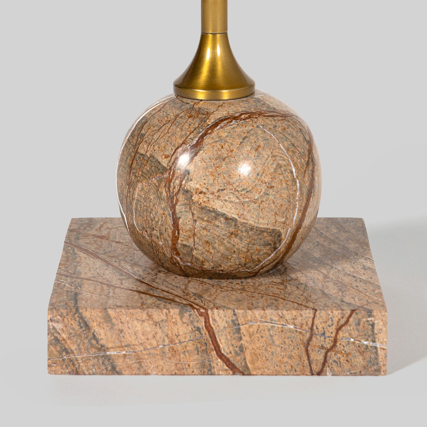 Small round cocktail table with marble top and brass base on a light gray background.