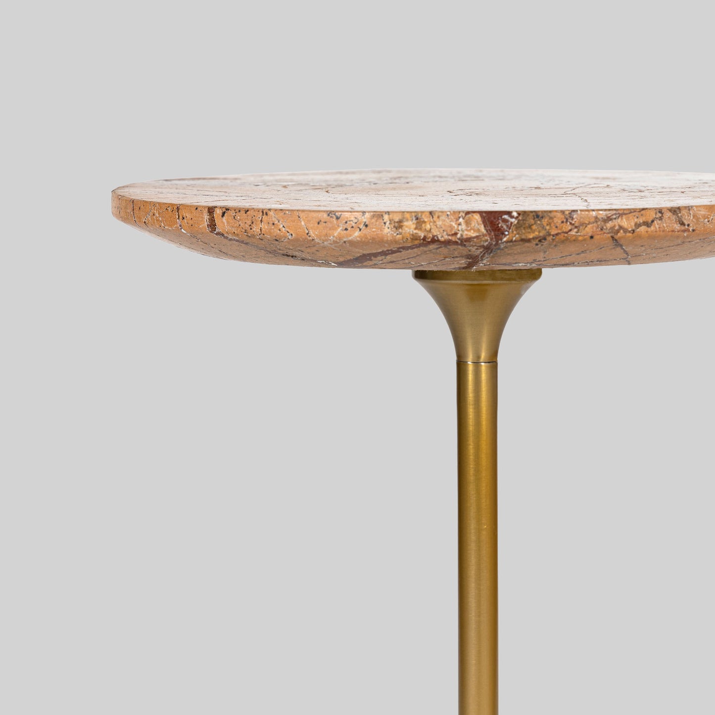 Small round cocktail table with marble top and brass base on a light gray background.
