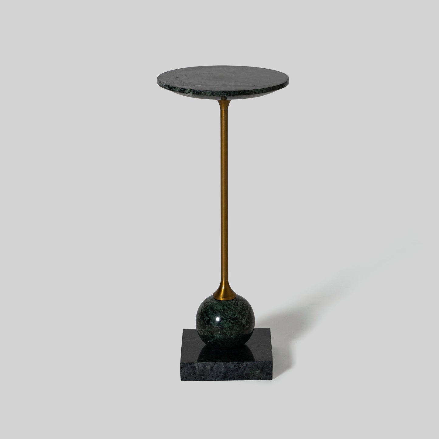 Small round cocktail table with marble top and brass base on a light gray background.