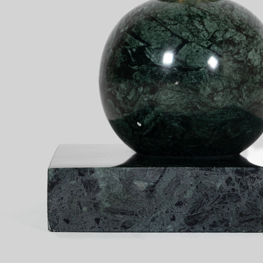 Small round cocktail table with marble top and brass base on a light gray background.