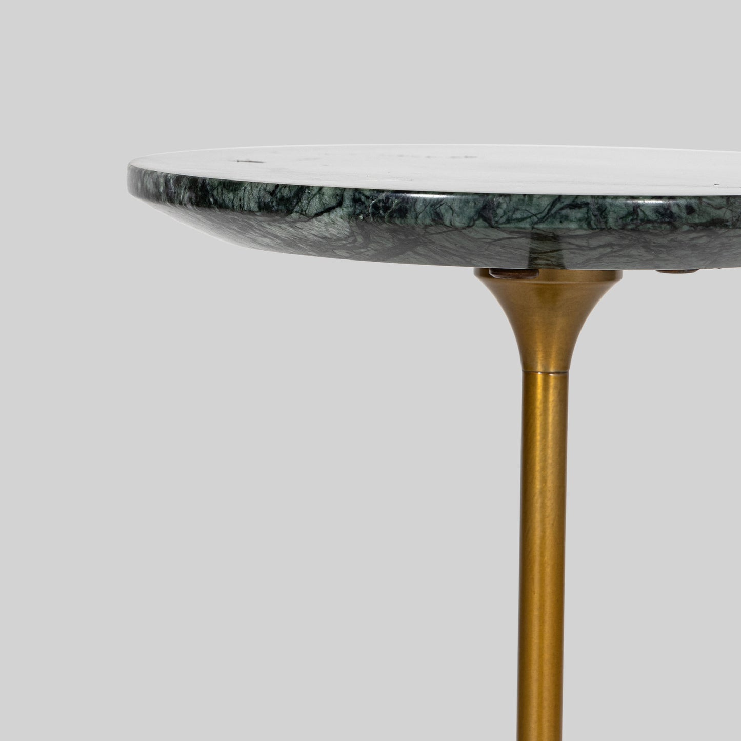 Small round cocktail table with marble top and brass base on a light gray background.