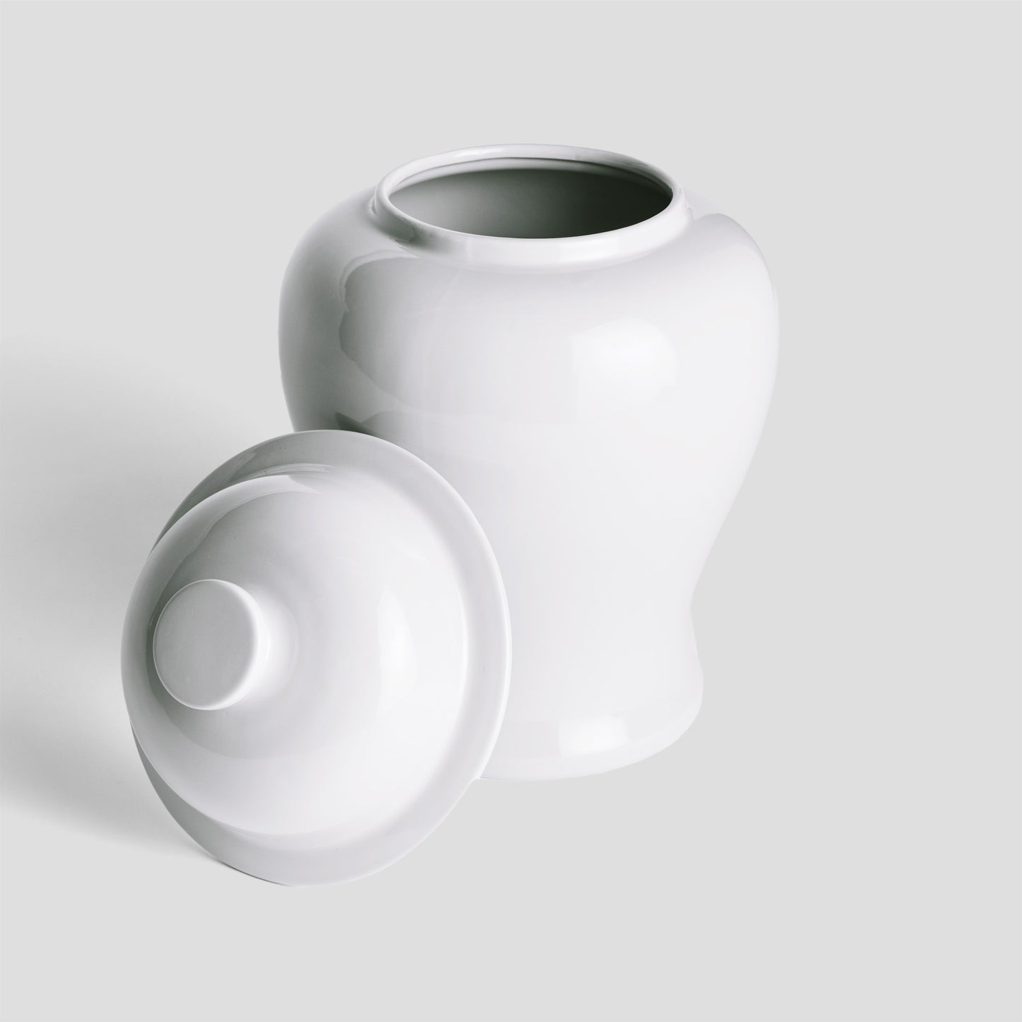 White ceramic lidded ginger jar, small, lid removed on gray background.