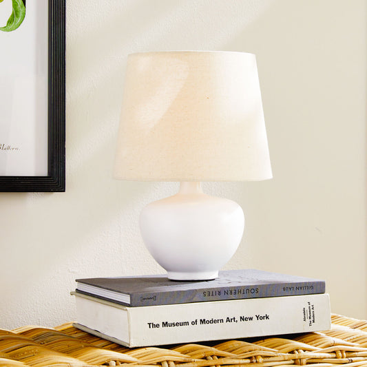 White ceramic mini lamp stylized on console table.