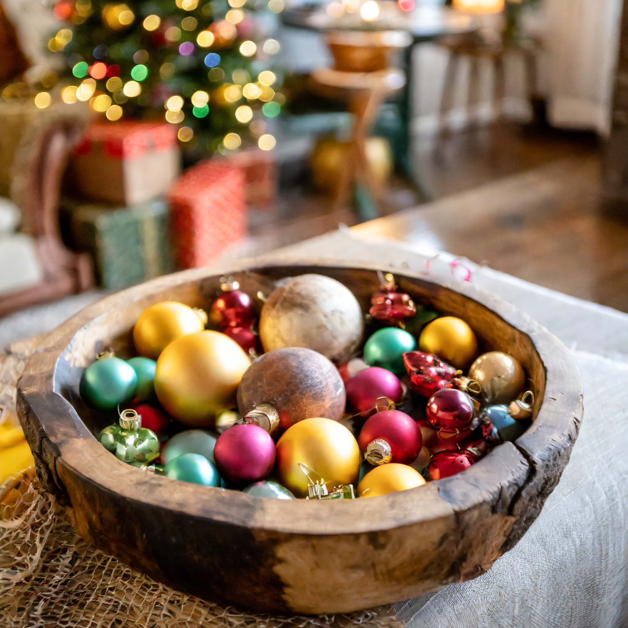 Wooden dough bowl filled with colored ornaments.