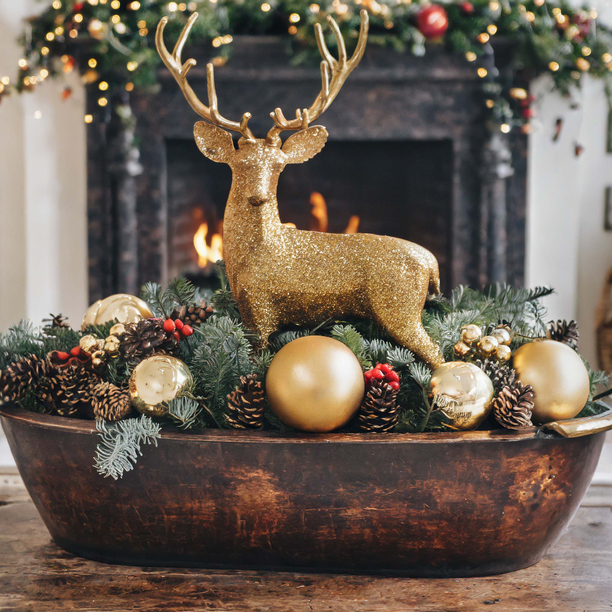 Wooden dough bowl filled with pine cones, gold balls, moss, and a gold reindeer.