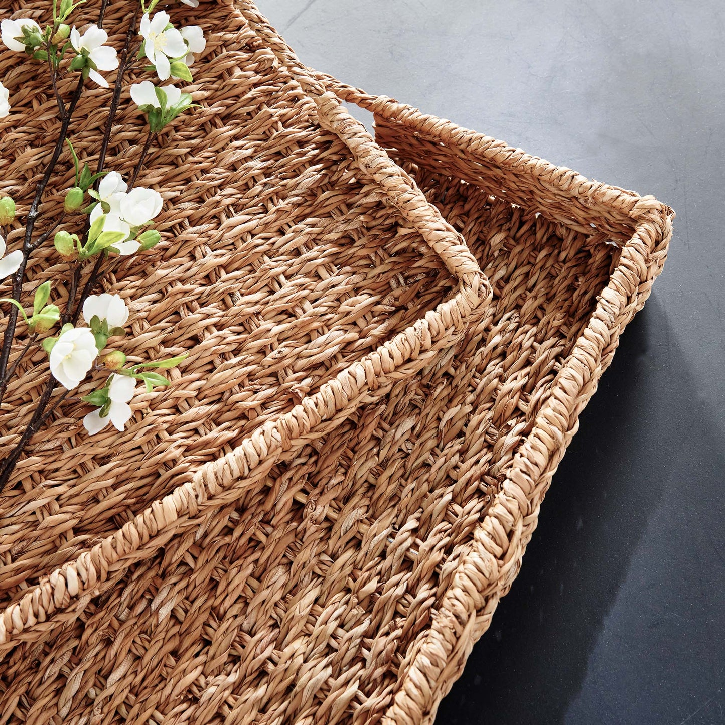 Woven seagrass rectangular tray set, top view closeup, on stone table.