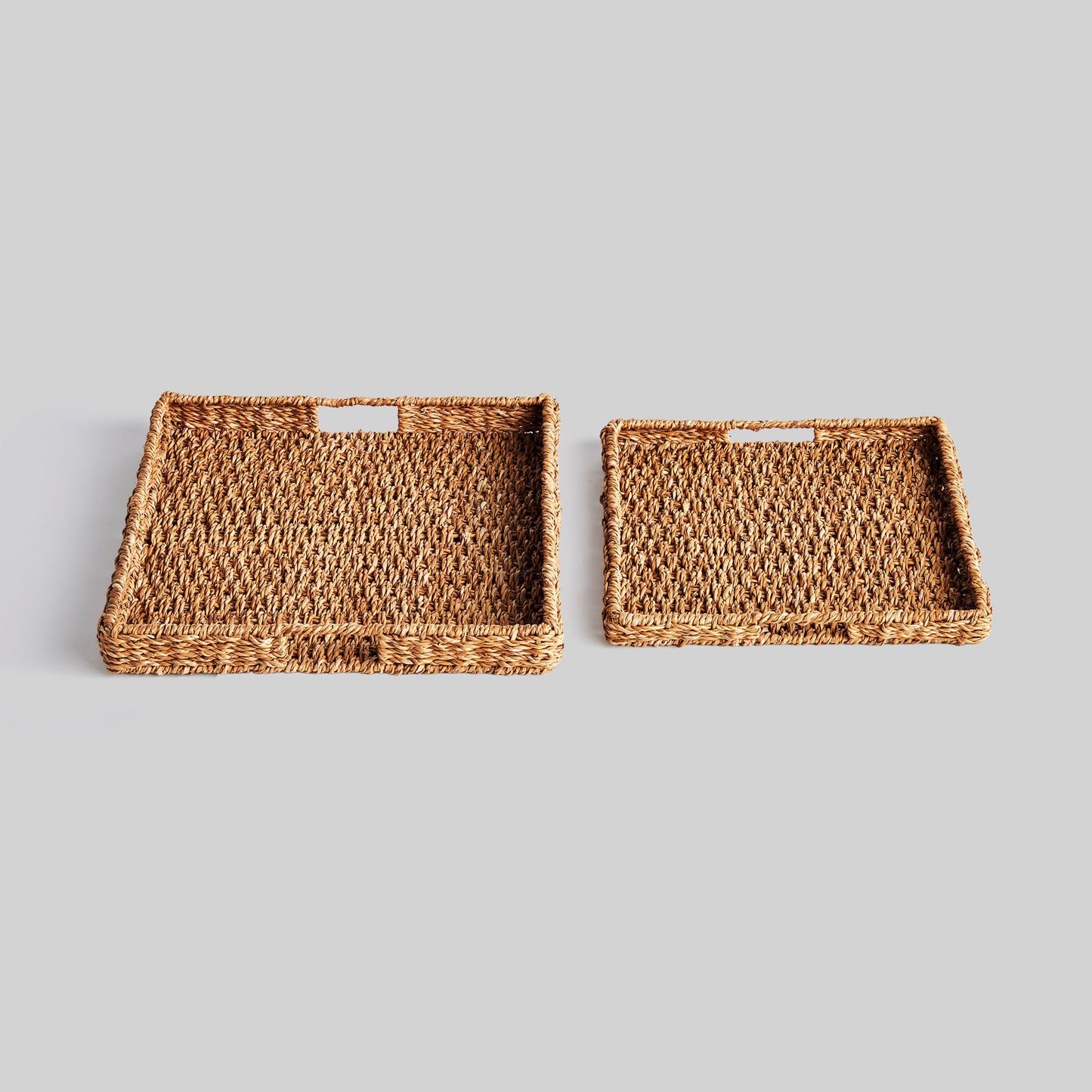 Woven seagrass rectangular tray set with gray background.
