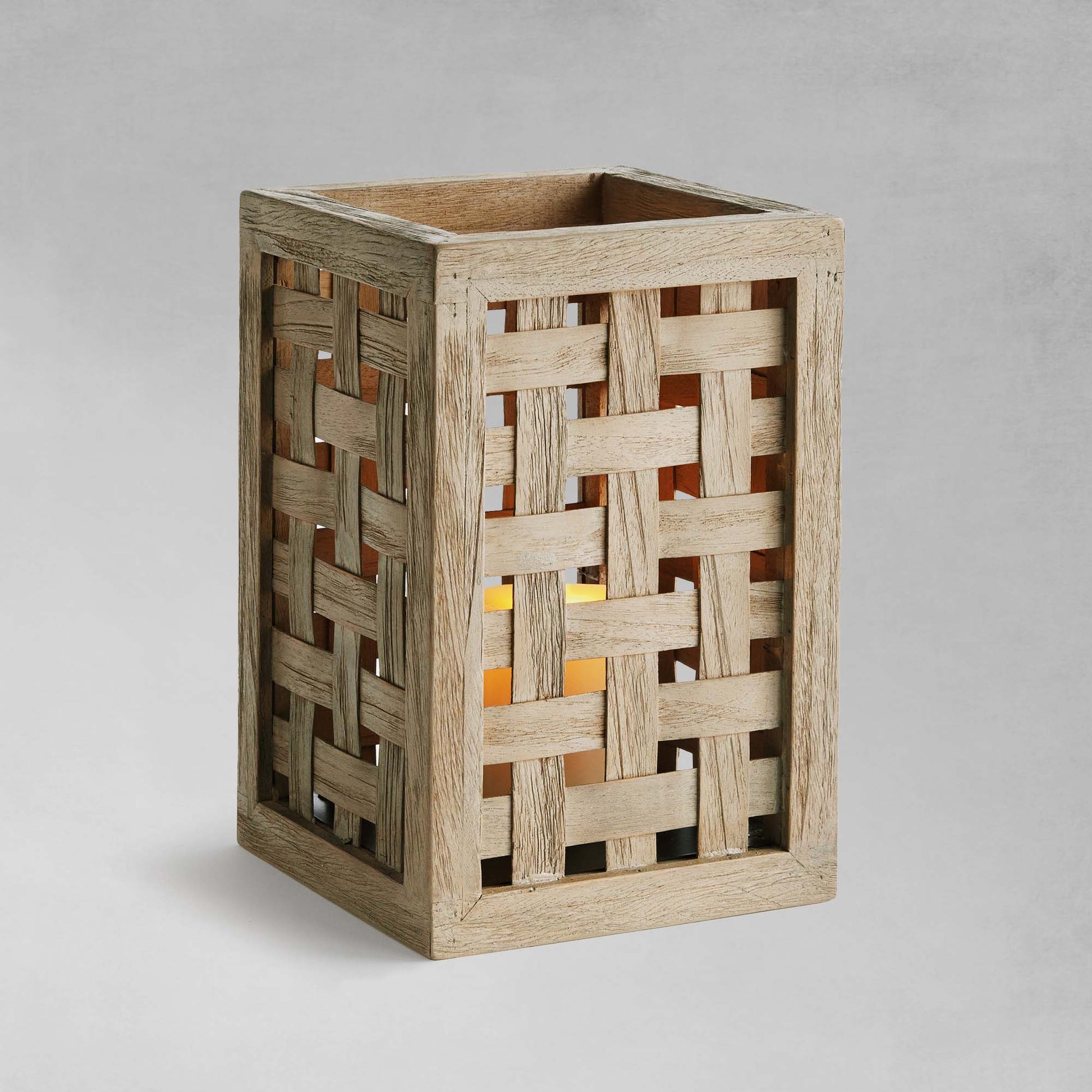 Woven teak hurricane candleholder with gray background.