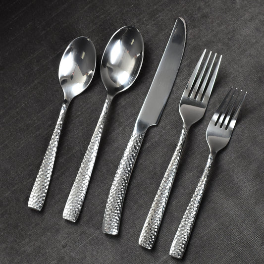 Polished silver hammered flatware on dark grey background.
