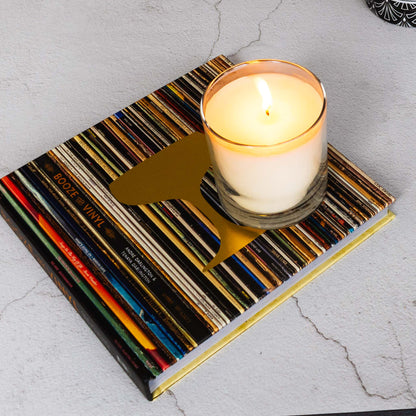 Luxury scented soy wax blend candle on Booze and Vinyl book on limestone table.