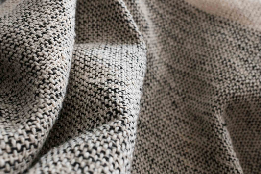 Cotton throw blanket with black and sand center block and sand border fabric closeup.